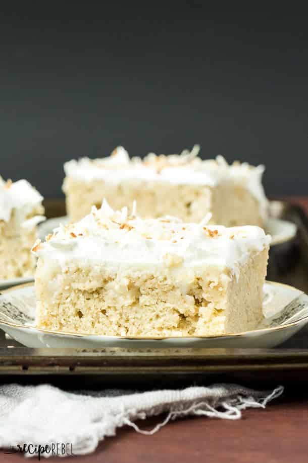 piece of coconut cream poke cake on white and gold saucer with another piece behind