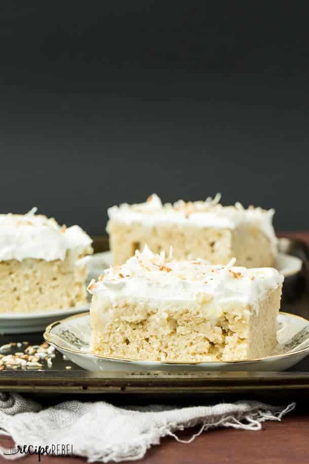 square piece of coconut cream poke cake topped with whipped cream and toasted coconut