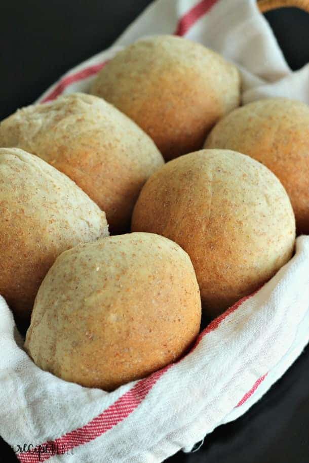 six whole wheat buns in basket lined with white and red towel