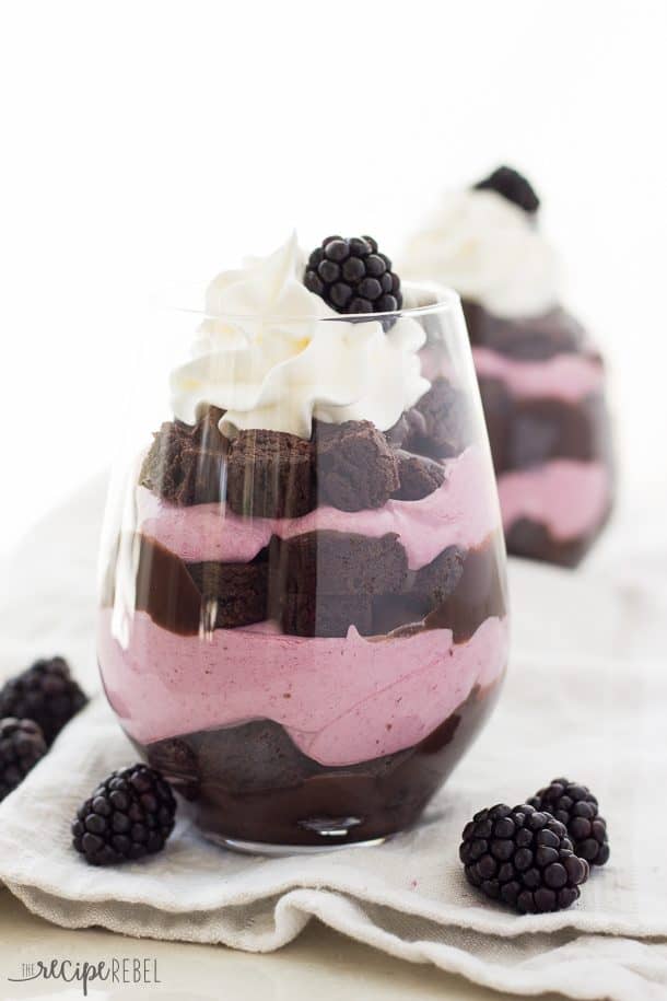 chocolate blackberry cheesecake trifles in stemless wine glasses with whipped cream and fresh blackberries