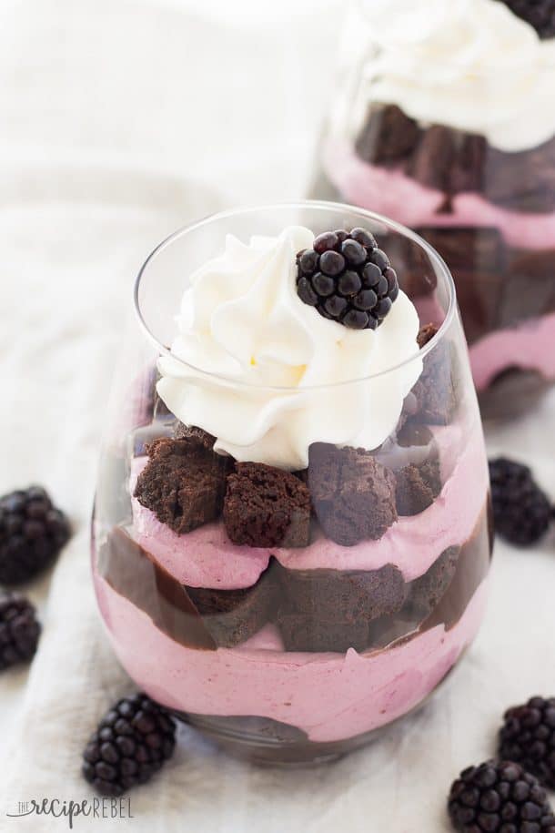 close up image of trifles with brownie pieces and no bake blackberry cheesecake filling in glass