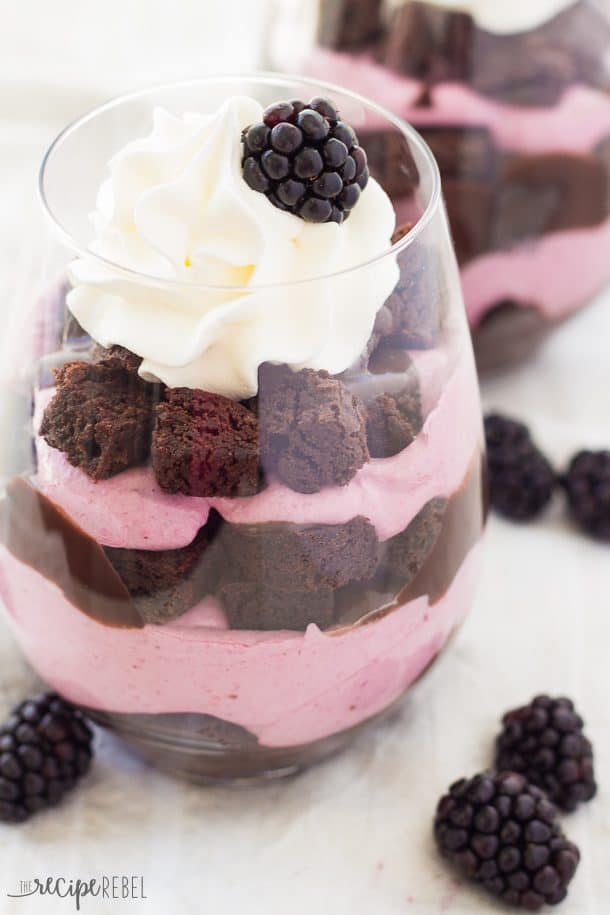 chocolate brownie blackberry cheesecake trifles in stemless wine glass topped with whipped cream