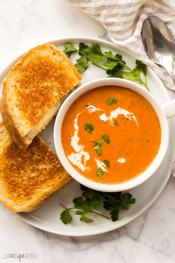 creamy tomato soup and grilled cheese on white plate