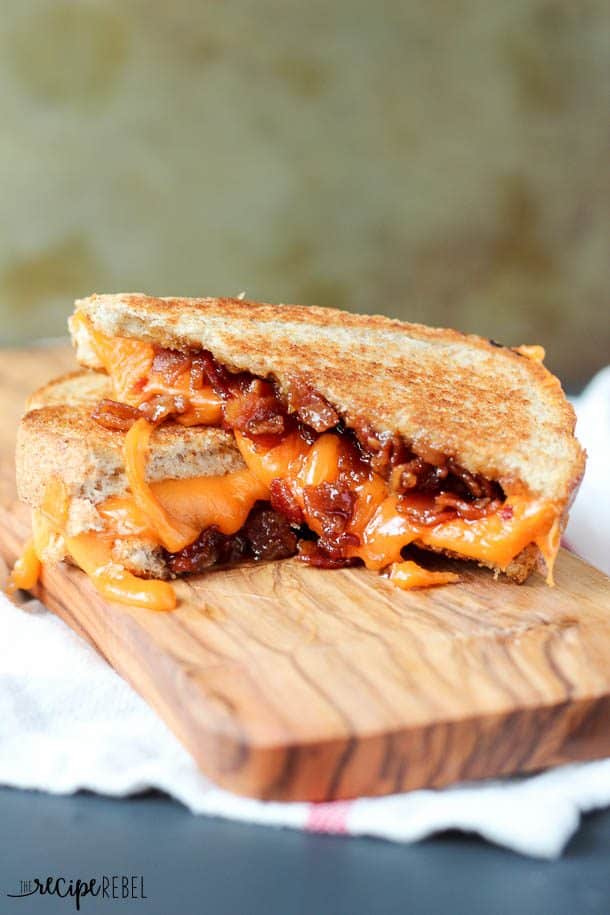 bacon jam grilled cheese cut open and stacked on wooden cutting board