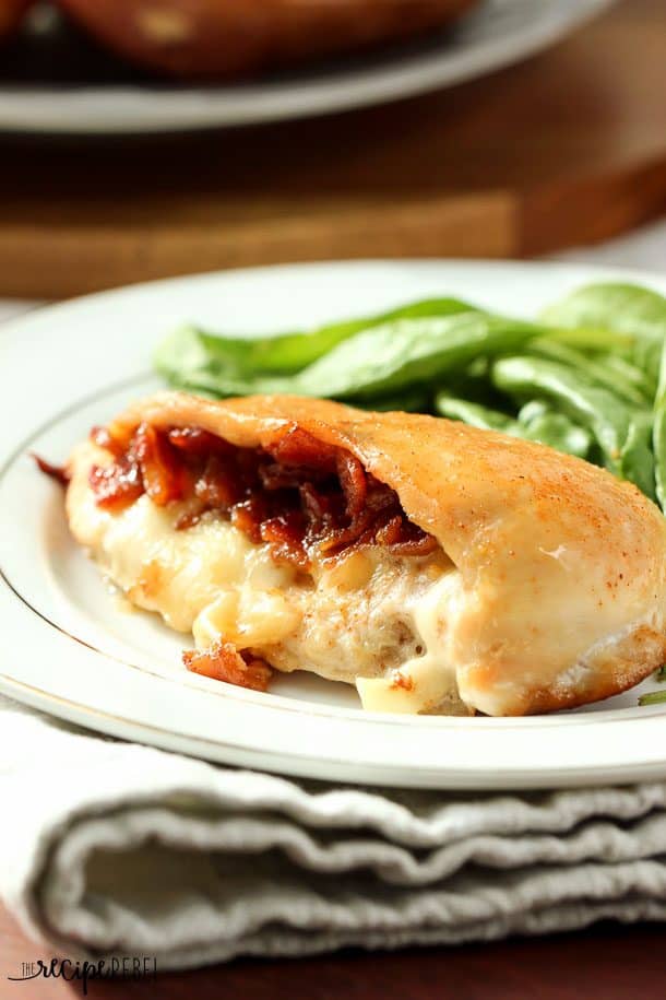 cheese and bacon jam stuffed chicken breasts with snap peas on the side on a white plate