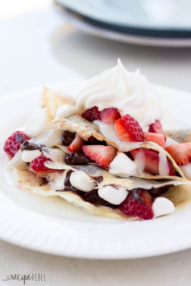 smores filled with chocolate marshmallows and strawberries and topped with whipped cream