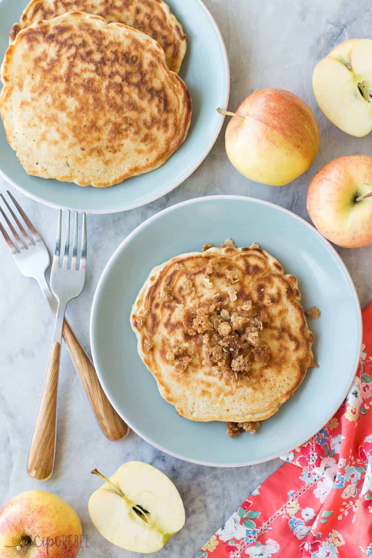 overhead image of apple crisp pancakes on blue plates with whole apples around
