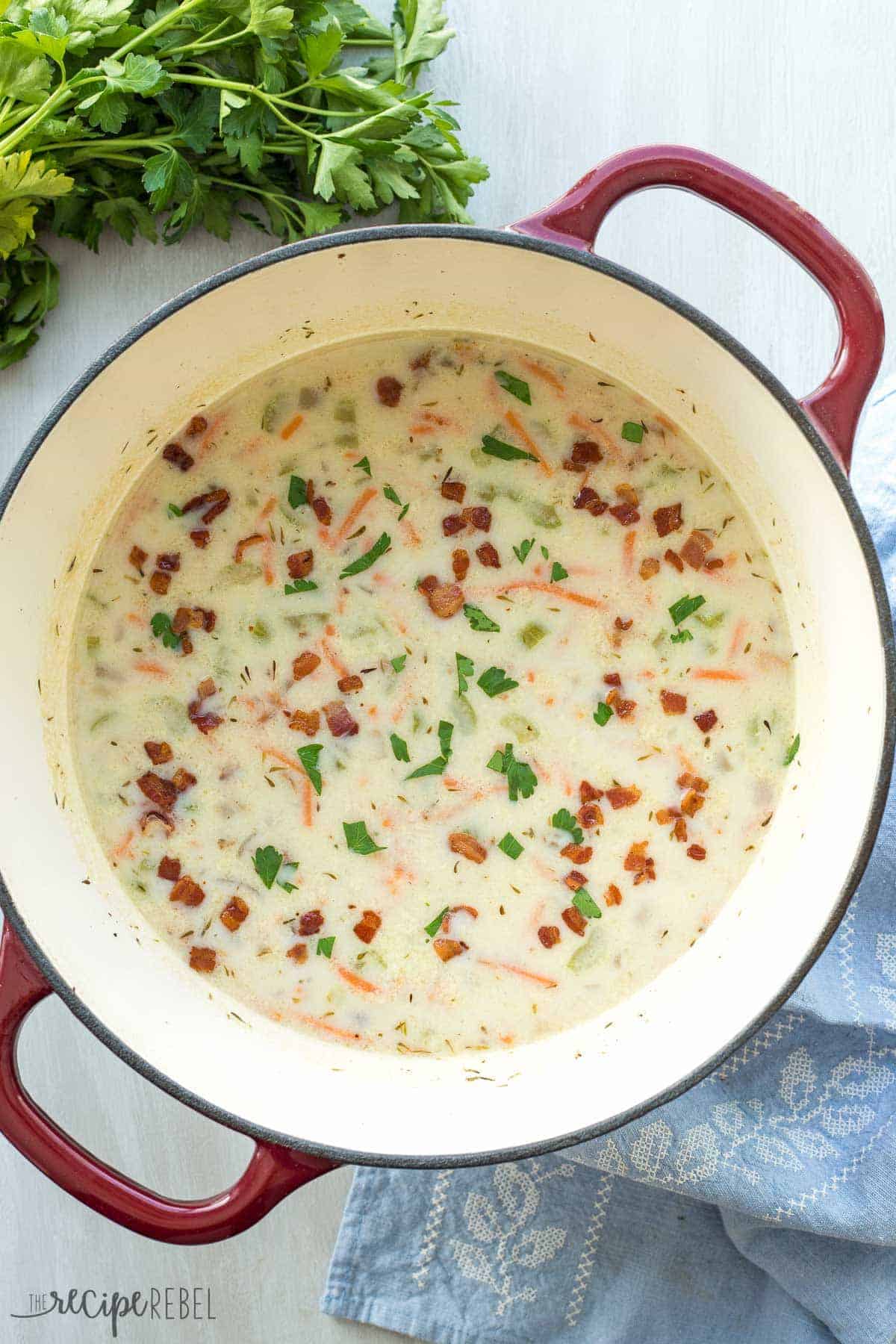 red and white dutch oven with quick chicken bacon rice soup and fresh parsley on the side