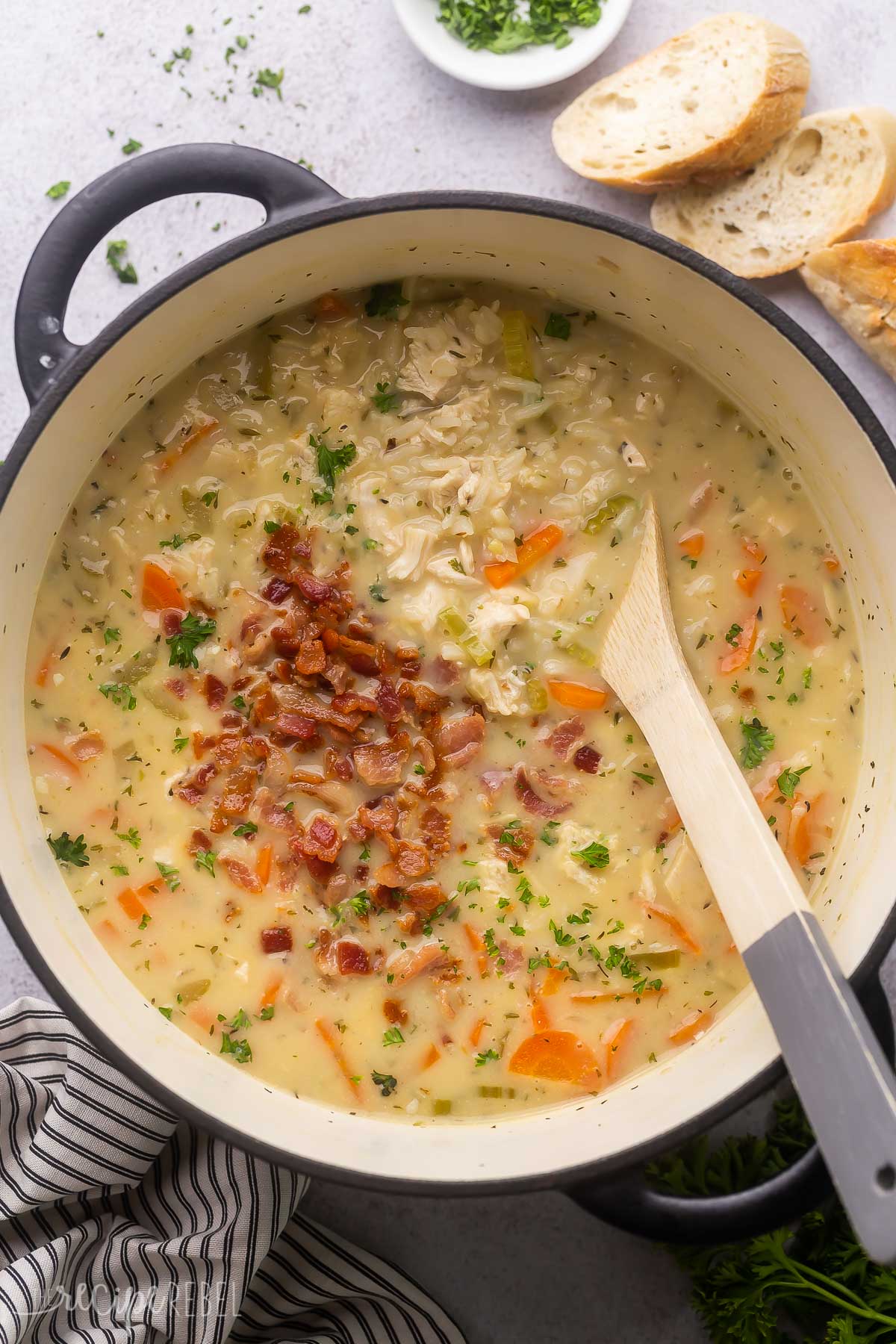 overhead image of chicken bacon rice soup with wooden spoon stuck in.

