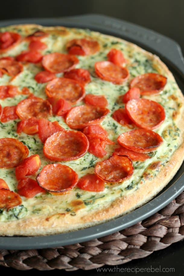 pizza with spinach alfredo sauce pepperoni and tomatoes on non stick pizza pan