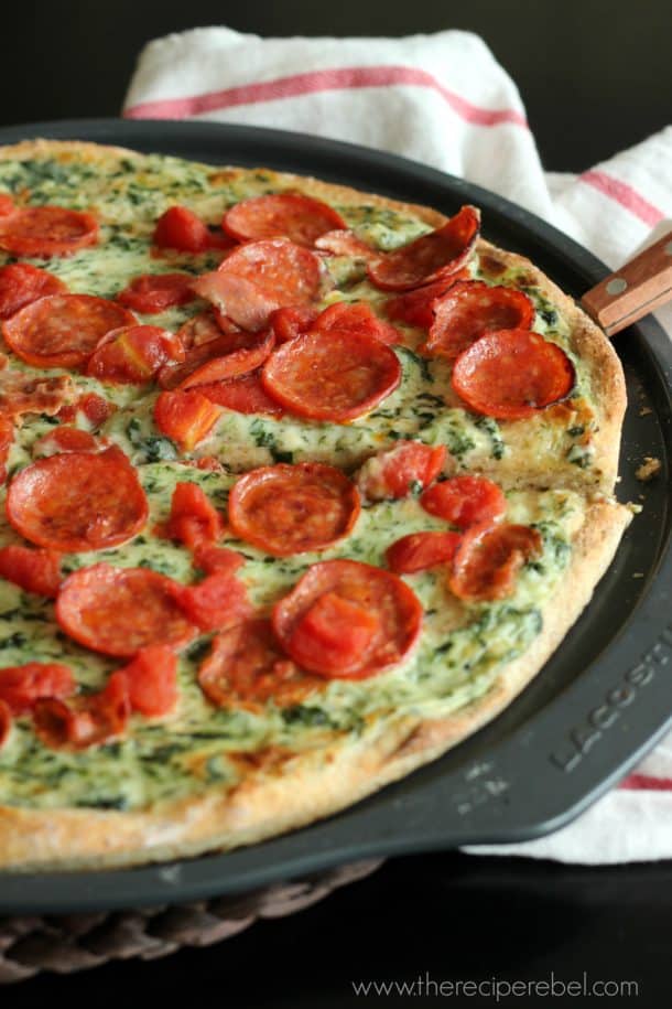 server scooping piece of pepperoni florentine pizza