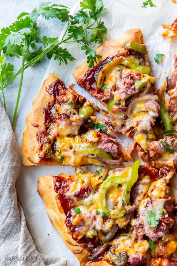 cheesesteak pizza cut into slices with parsley on the side