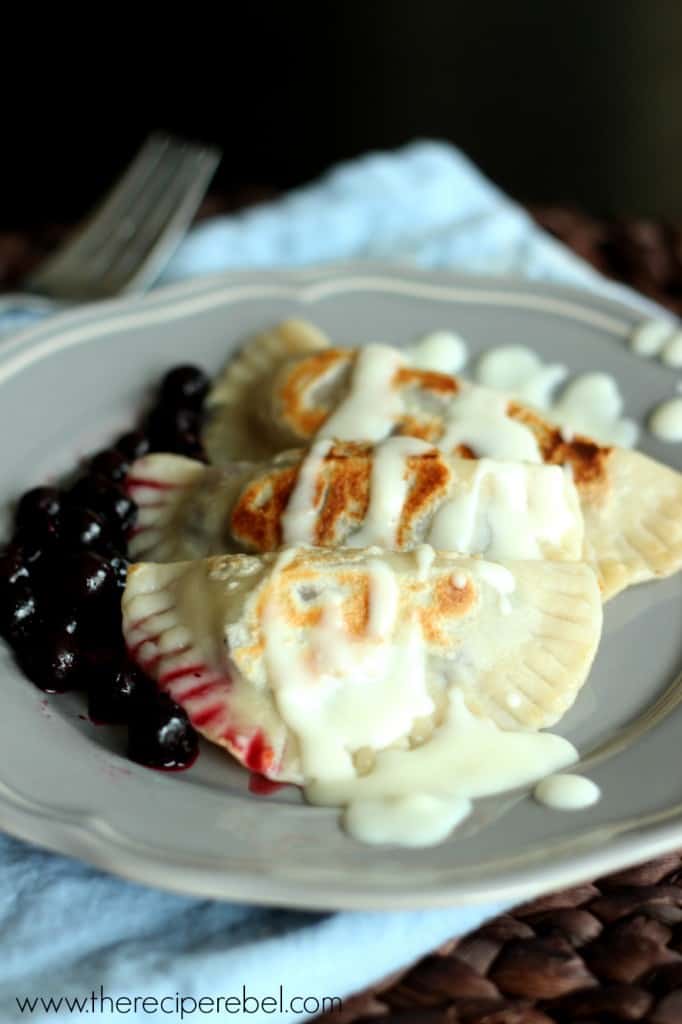 homemade saskatoon perogies on grey plate with cream sauce on top