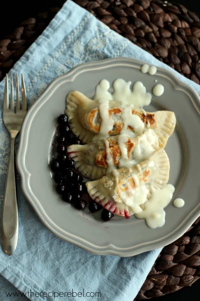 overhead image of three saskatoon perogies on grey plate drizzled with cream gravy