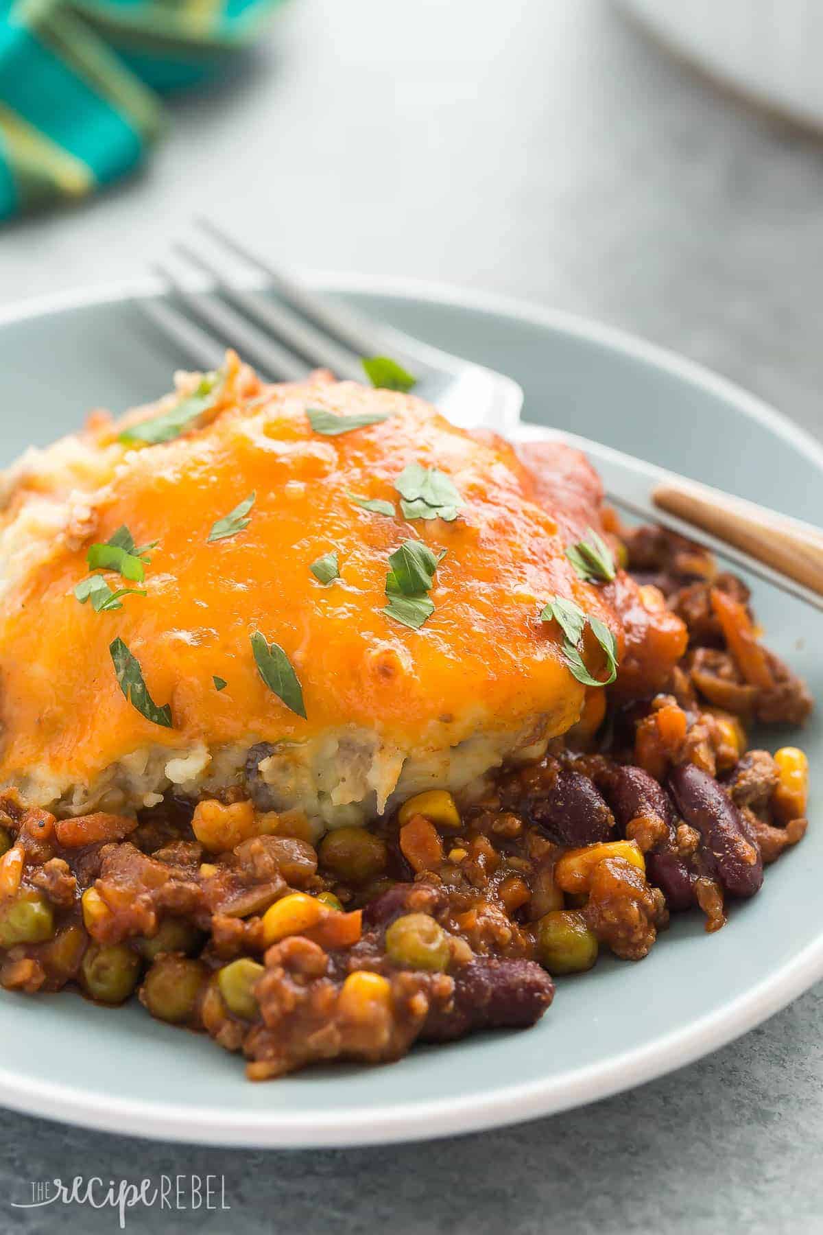 blue plate with bbq chili shepherd's pie with melted cheddar cheese and fresh parsley