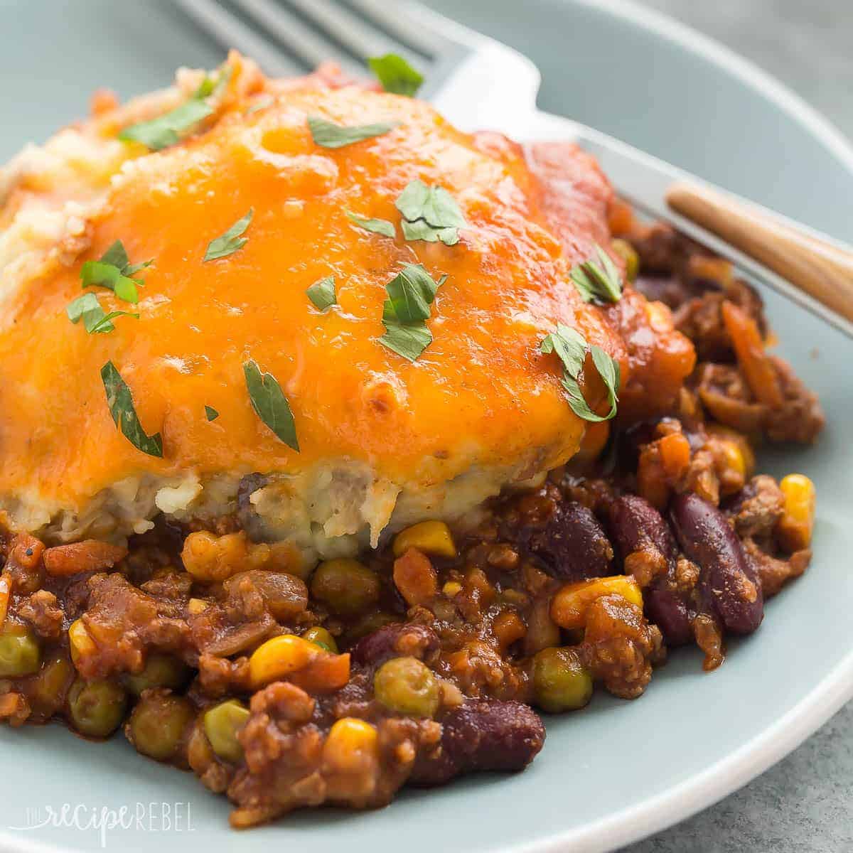 square image of a blue plate of bbq chili shepherd's pie with fork on the side