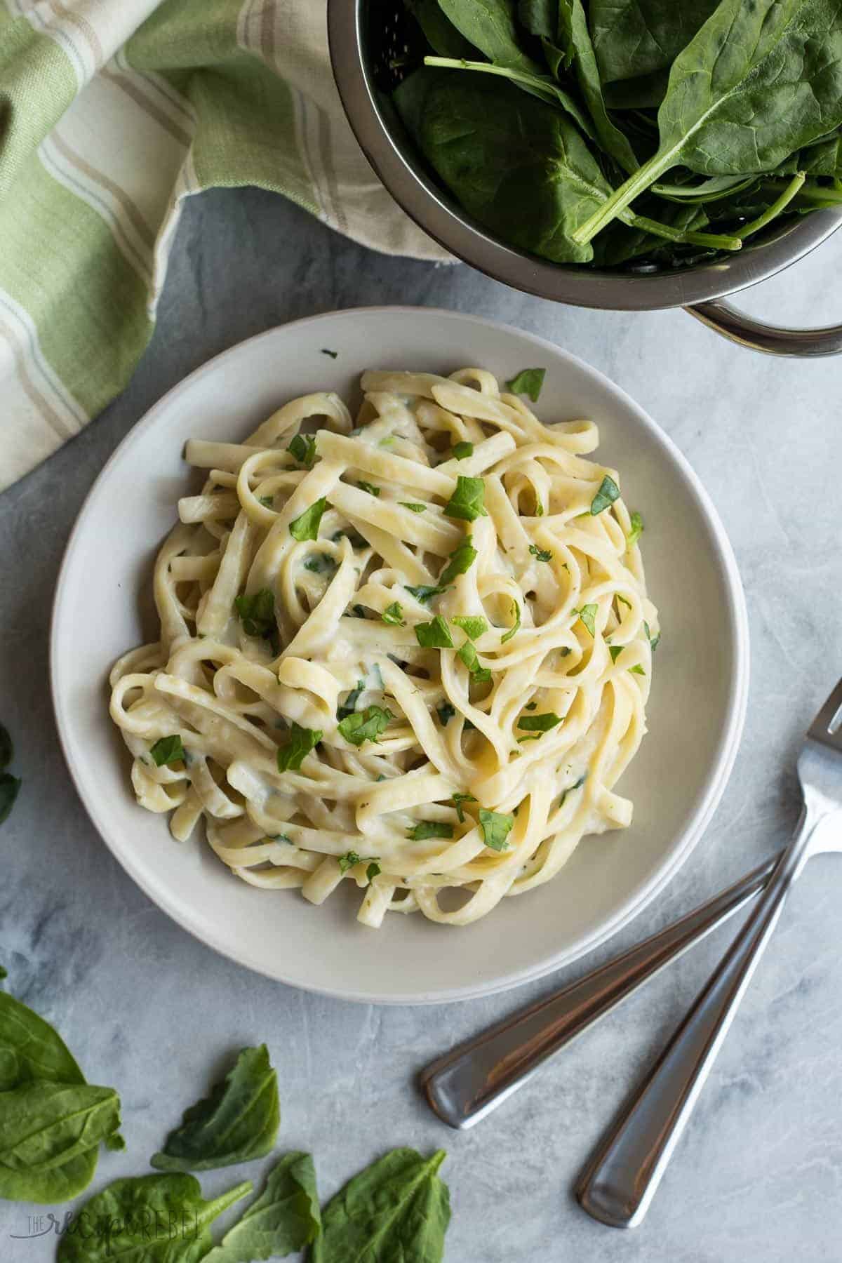 fettuccinie with light alfredo sauce and chopped spinach on grey plate