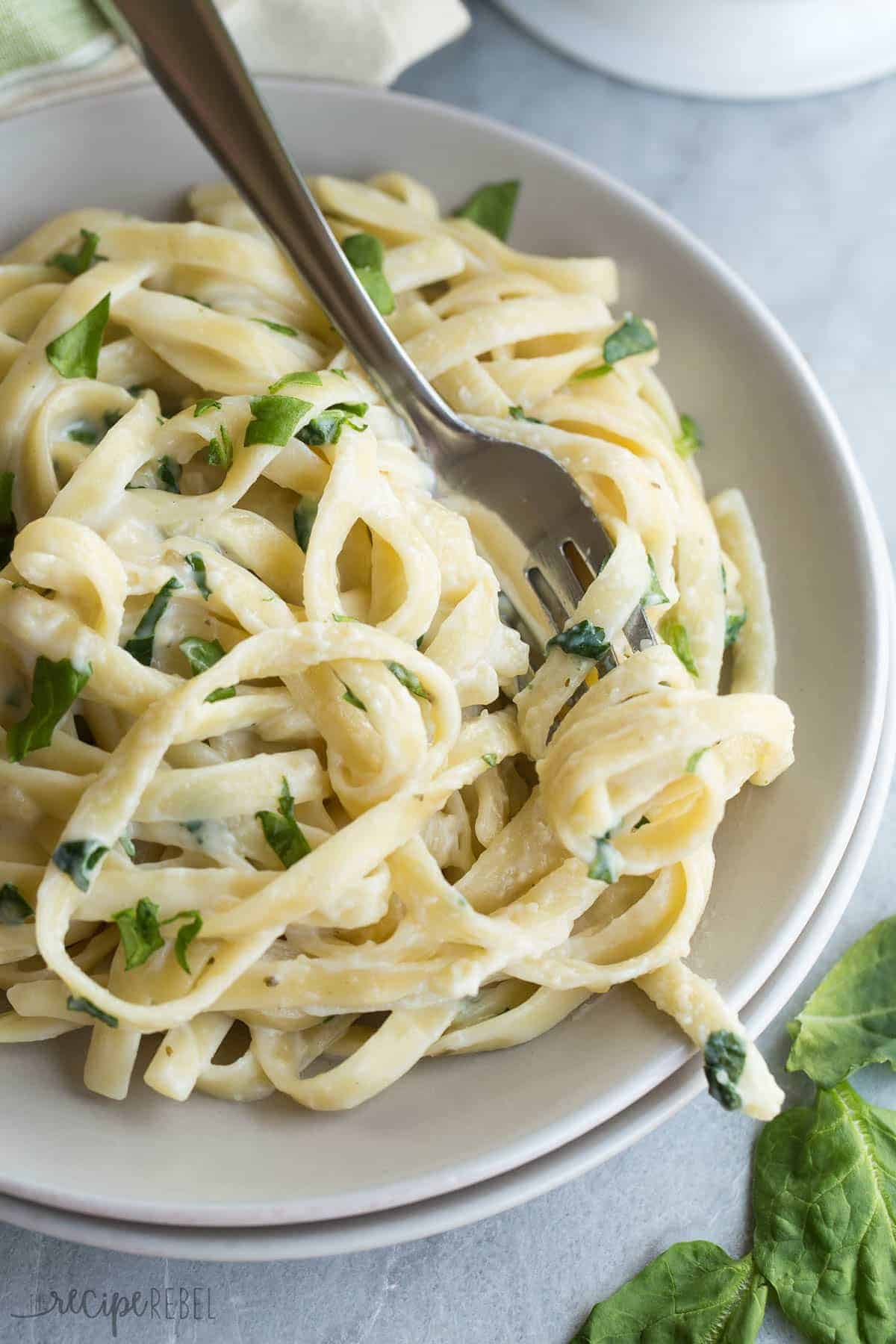 peso spinach alfredo sauce over fettuccine on grey plate