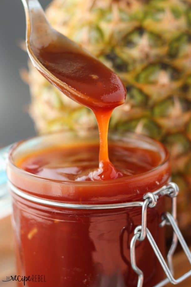 spoon drizzling barbecue sauce back into jar with pineapple behind