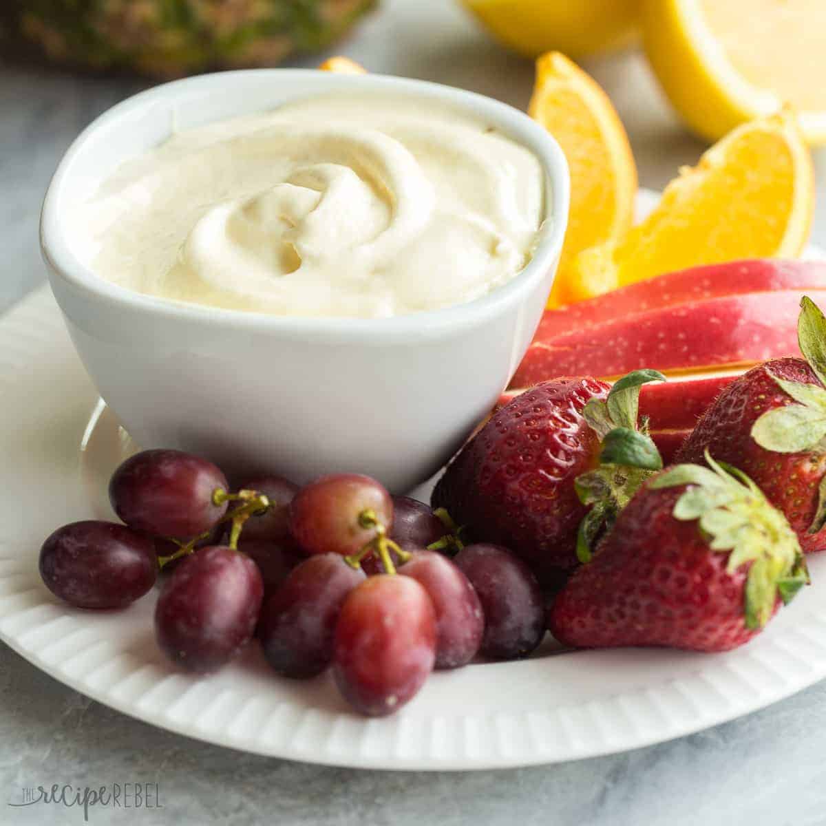 square image of pineapple lemonade fruit dip with fruit all around on white plate