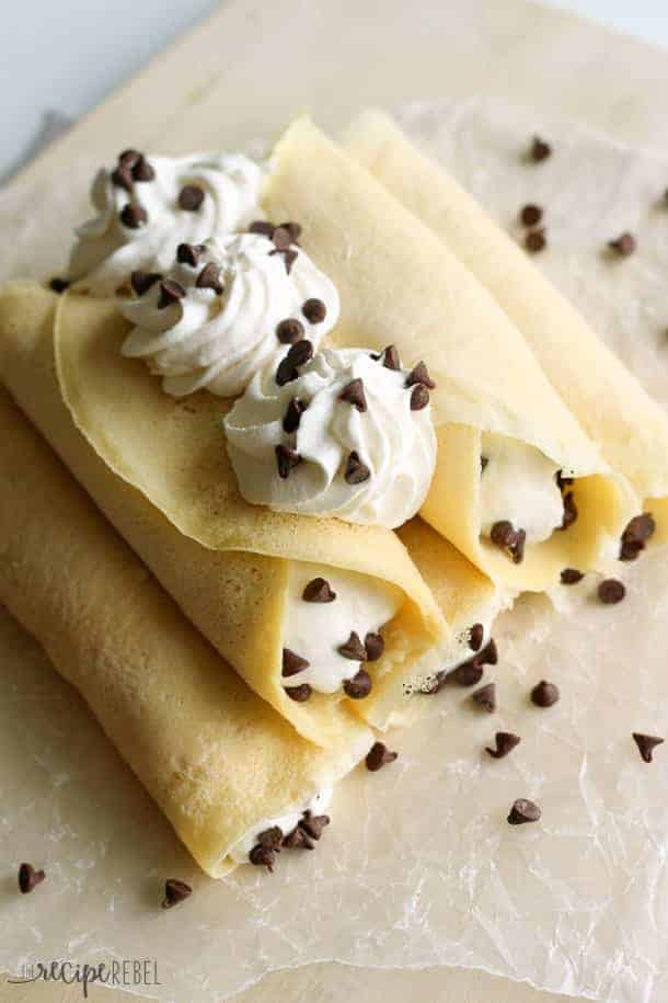 overhead image of cannoli crepes stacked on wooden cutting board