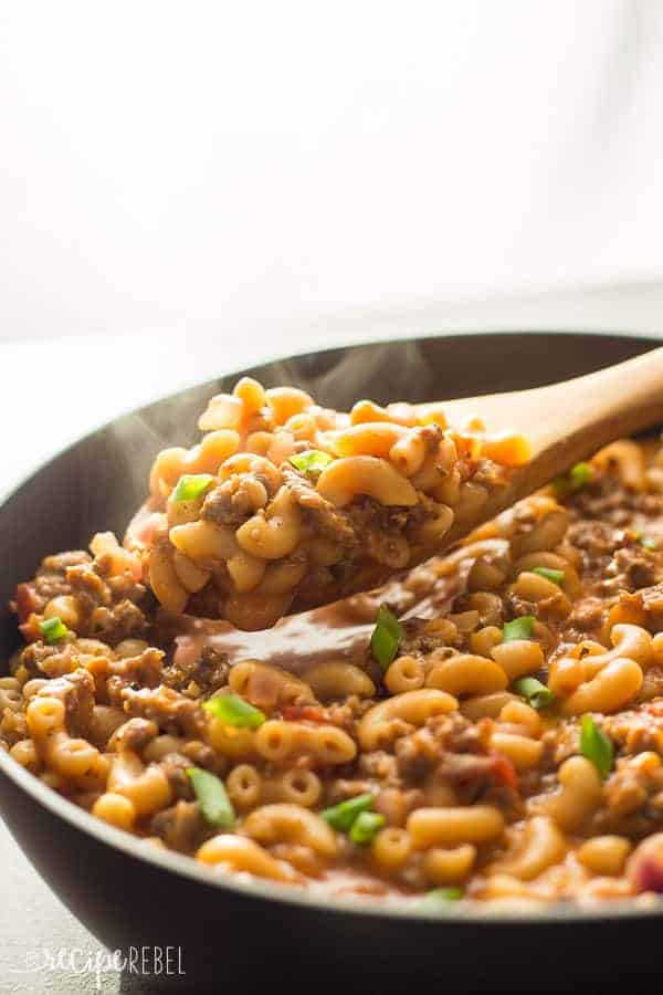 wooden spoon scooping hamburger helper out of black skillet