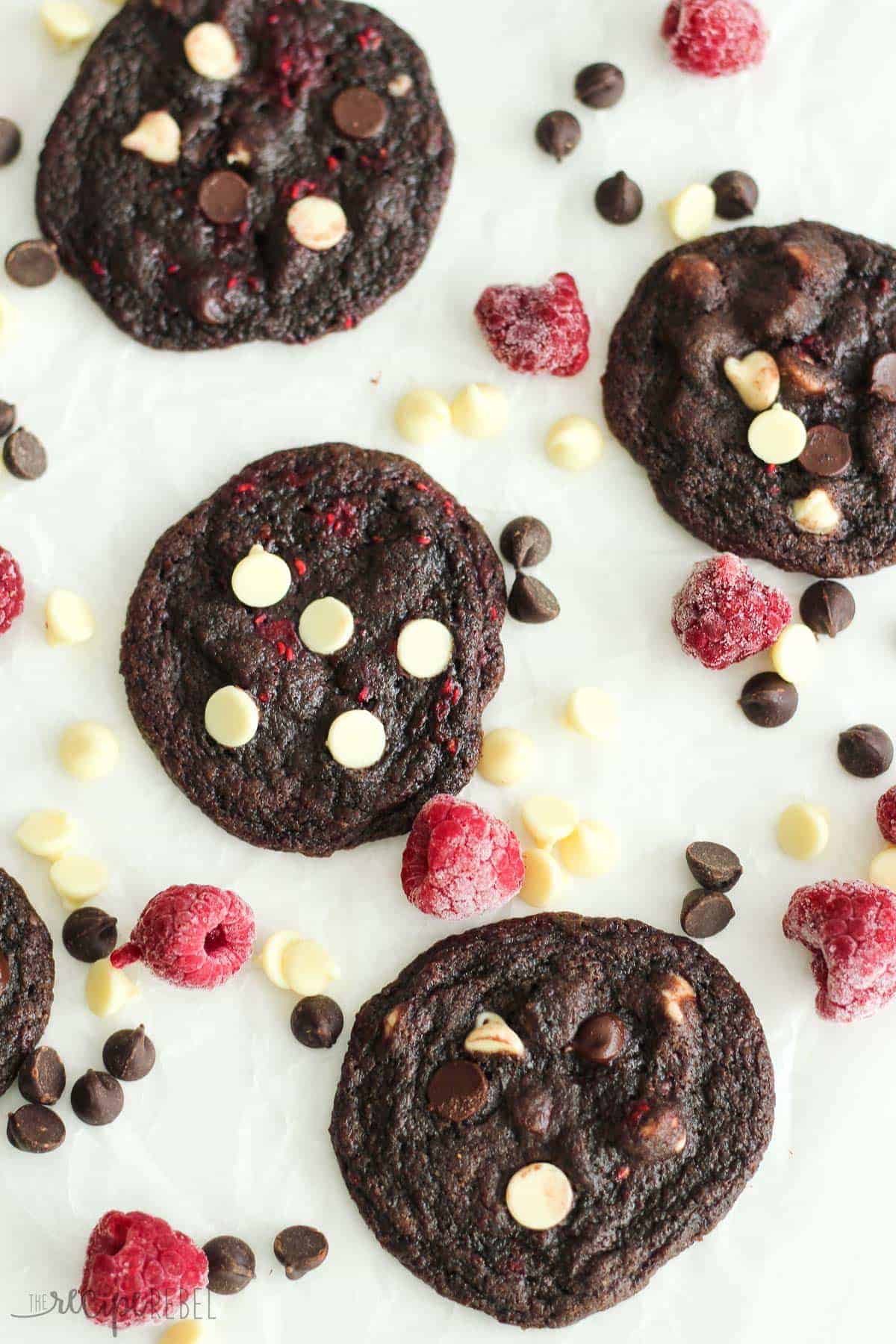 overhead image of triple chocolate raspberry cookies with frozen raspberries and chocolate chips around