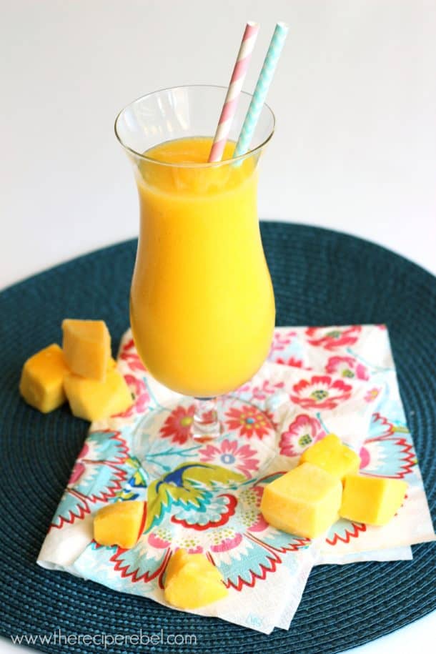 mango slush in tall glass with frozen mango chunks all around