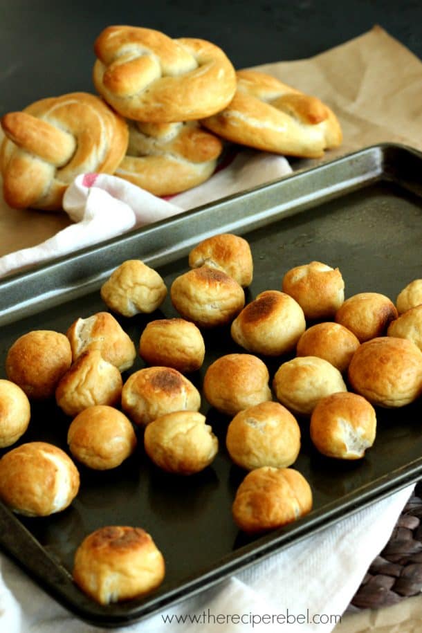 soft pretzel bites on baking sheet with full soft pretzels in the background