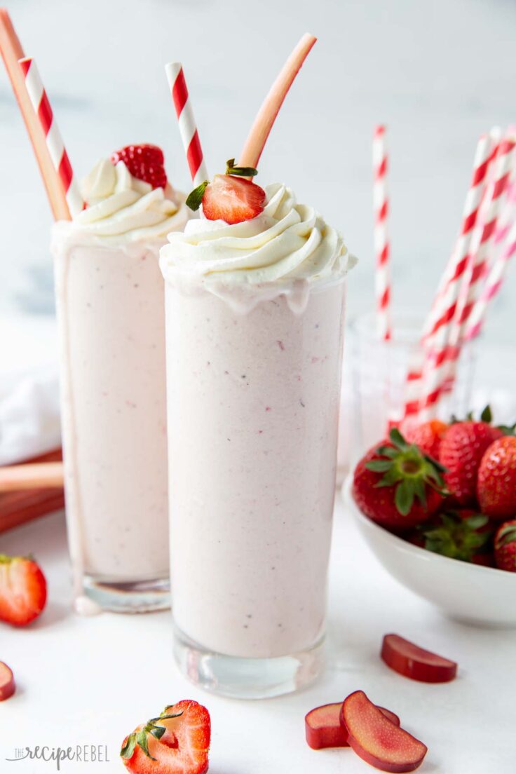 Roasted Strawberry Rhubarb Milkshakes are a fun way to celebrate spring fruit! Sweet and creamy with the perfect amount of tang from the rhubarb. #rhubarb #strawbrries | rhubarb recipes | strawberry recipes two strawberry rhubarb milkshakes in glasses with whipped cream