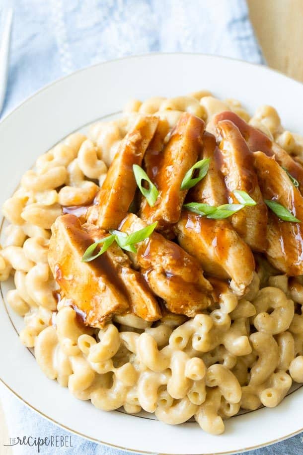sliced barbecue chicken over a bed of creamy mac and cheese on a white plate