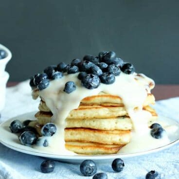 Blueberries 'n' Cream Pancakes: Super easy, fluffy pancakes topped with vanilla custard sauce and fresh blueberries! The perfect breakfast to use up those summer berries. www.thereciperebel.com