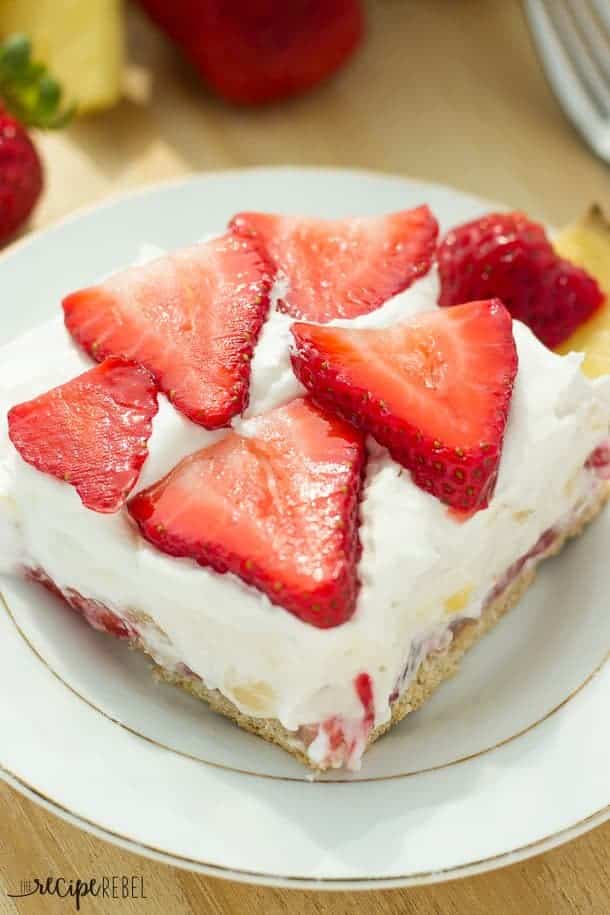 white plate with strawberry pineapple cheesecake piece topped with strawberry slices