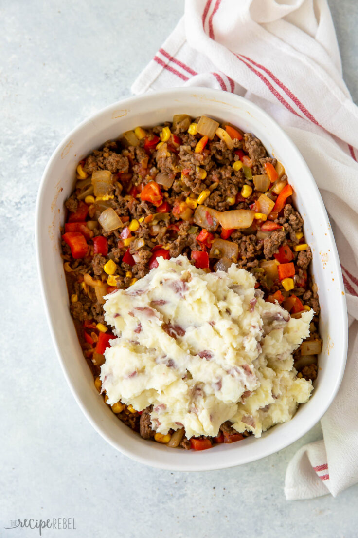 mashed potatoes being spread over shepherds pie filling