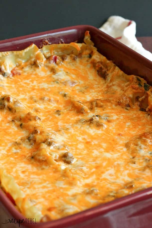 close up image of chipotle sausage lasagna in baking dish with lots of melted cheese