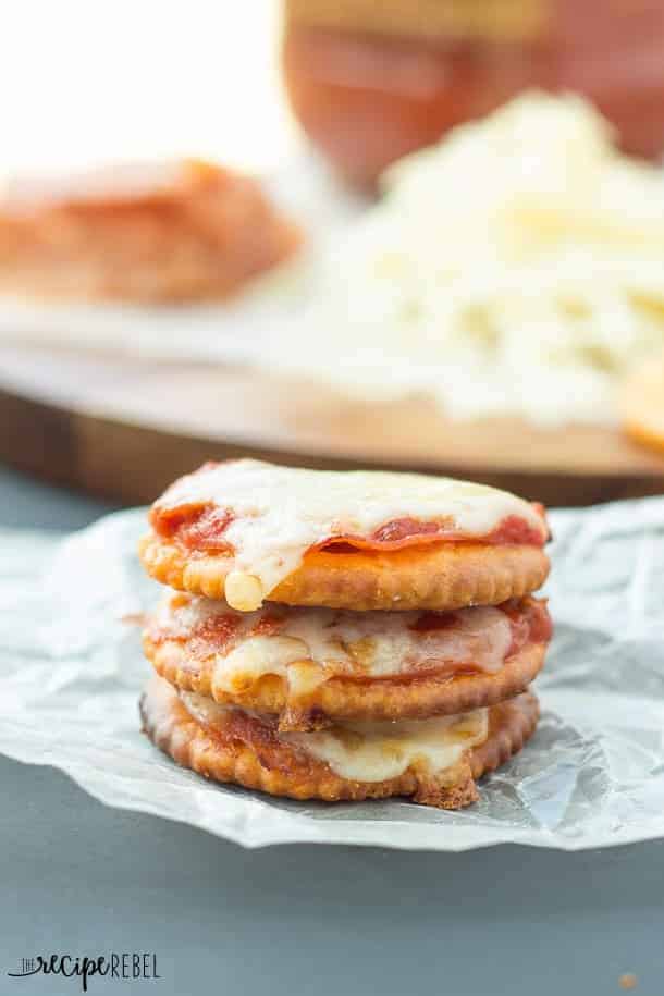 Pizza Crackers: The easiest 4-ingredient snack, appetizer or lunch for the kids! Easily change them to your tastes. Less than 10 minutes start to finish! www.thereciperebel.com three stacked pizza crackers made with ritz crackers pepperoni and mozzarella on parchment paper