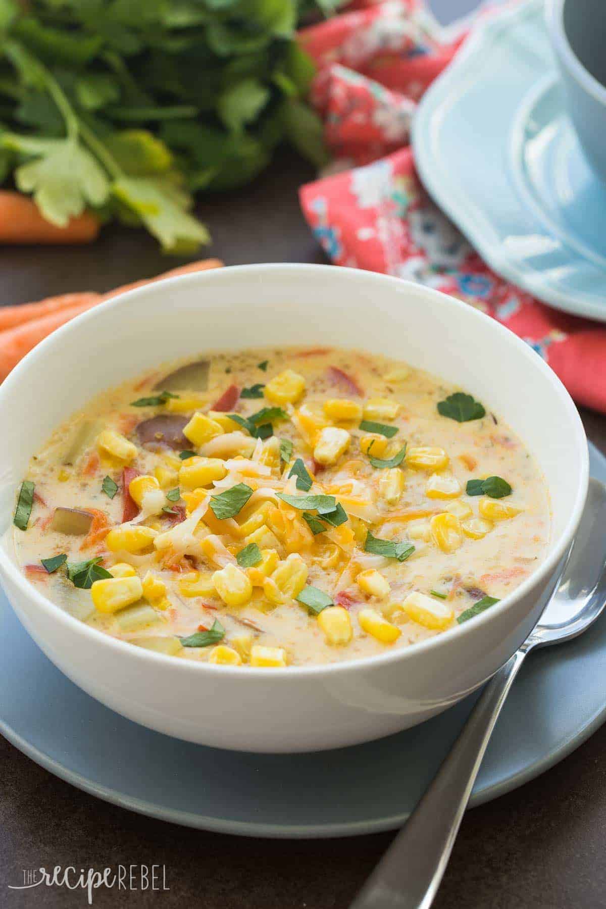 quinoa corn chowder in white bowl on grey plate with spoon on the side