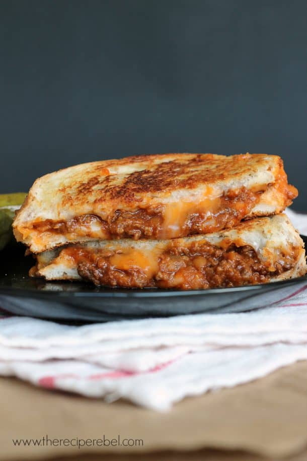 sloppy joe grilled cheese cut in half stacked on a black plate