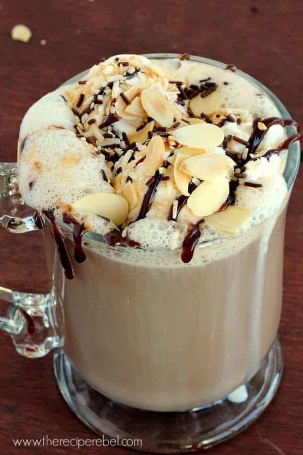 glass mug with almond joy mocha topped with coconut cream almonds and chocolate sauce