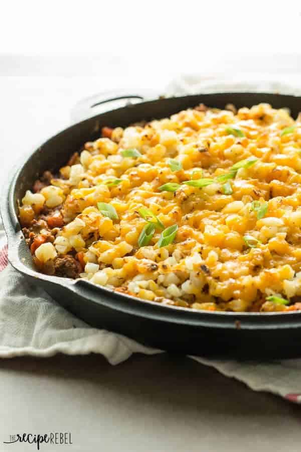 An easy, one skillet Mexican dish that the whole family will love! Made easier with frozen hashbrown potatoes and packed with hidden veggies! taco beef and potato skillet in cast iron skillet on white background