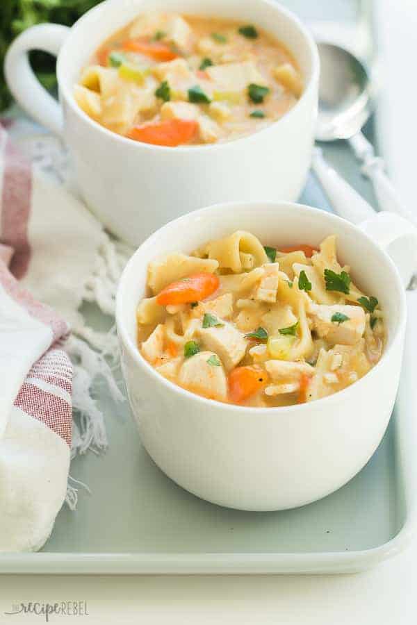 creamy chicken noodle soup in two mugs close up