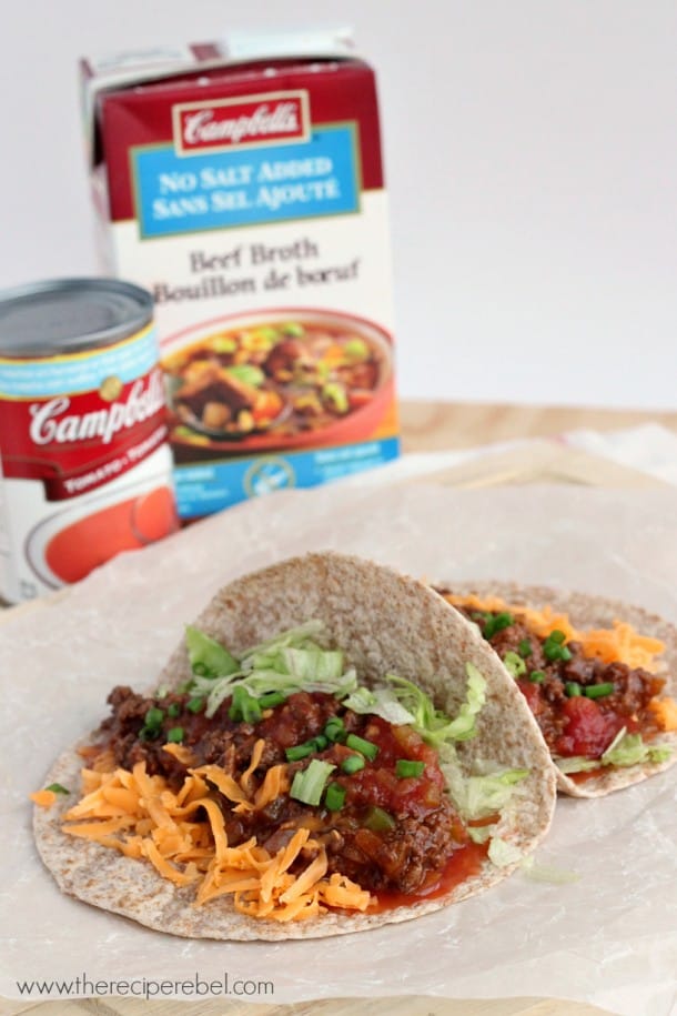 two whole wheat tortillas with taco meat cheese salsa and lettuce in front of campbells soup