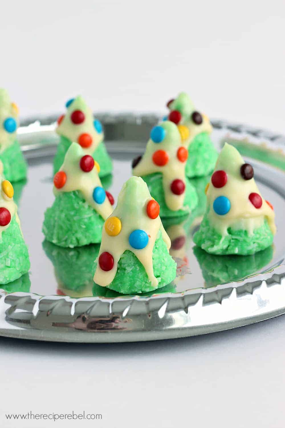 no bake christmas tree cookies on silver tray decorated with white chocolate and mini m&ms