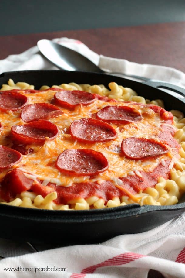 cast iron skillet with mac and cheeses topped with pizza sauce and pepperoni