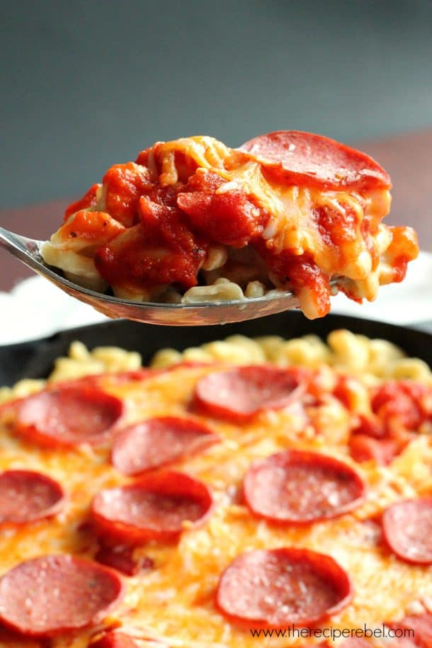 metal spoon scooping pepperoni pizza mac and cheese above skillet
