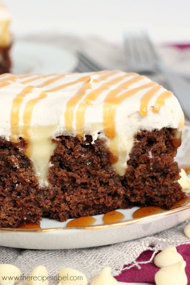 close up of white chocolate gingerbread poke cake with whipped cream and caramel sauce