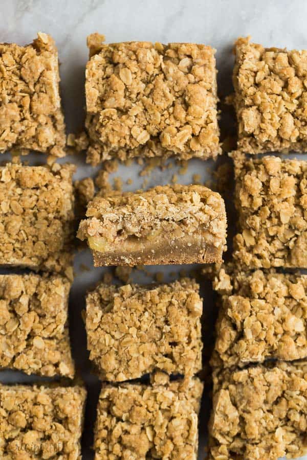 These Apple Crisp Blondies are an apple crisp bar with a blondie base -- the perfect combo of chewy blondie, tender apples, and crispy streusel! #apple #dessert #recipes #fall apple crisp blondies overhead cut into squares with one square tilted on its side