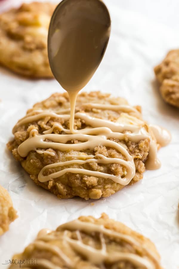 glaze being drizzled on apple crisp cookie on parchment paper