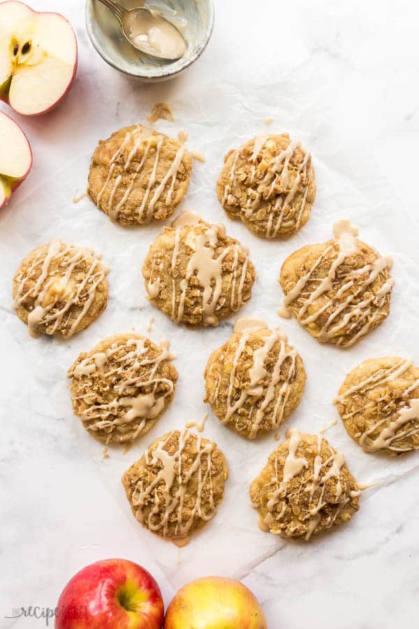 overhead image of glazed apple crisp cookies on parchment with fresh apples