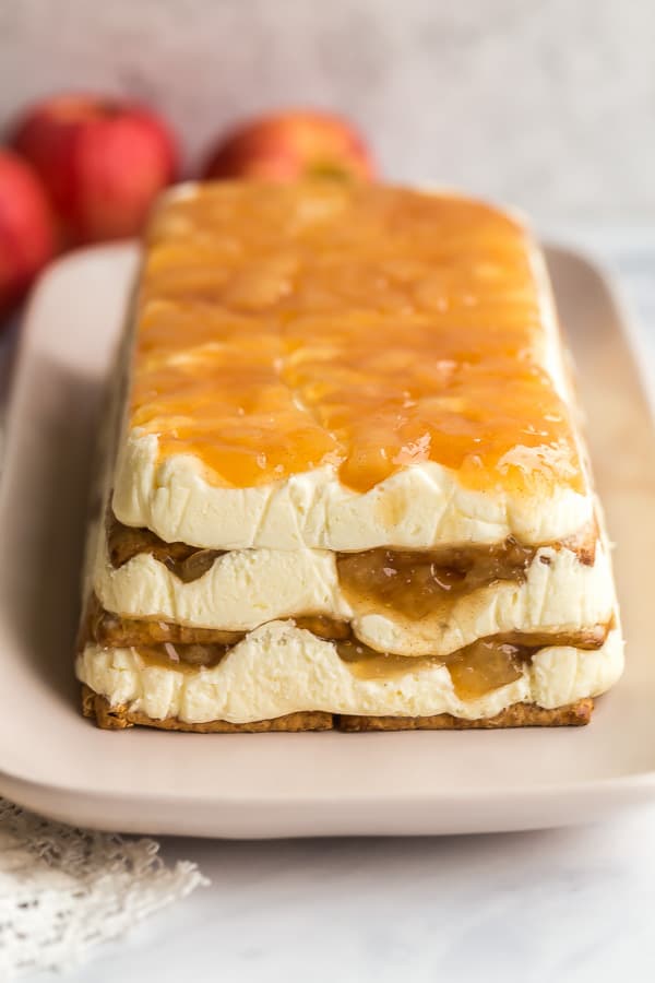 This Caramel Apple Icebox Cake is made with layers of graham crackers, cream cheese, apple pie filling and topped with a drizzle of caramel. An easy no bake dessert! #apple #cake #dessert #nobake caramel apple icebox cake on pink platter